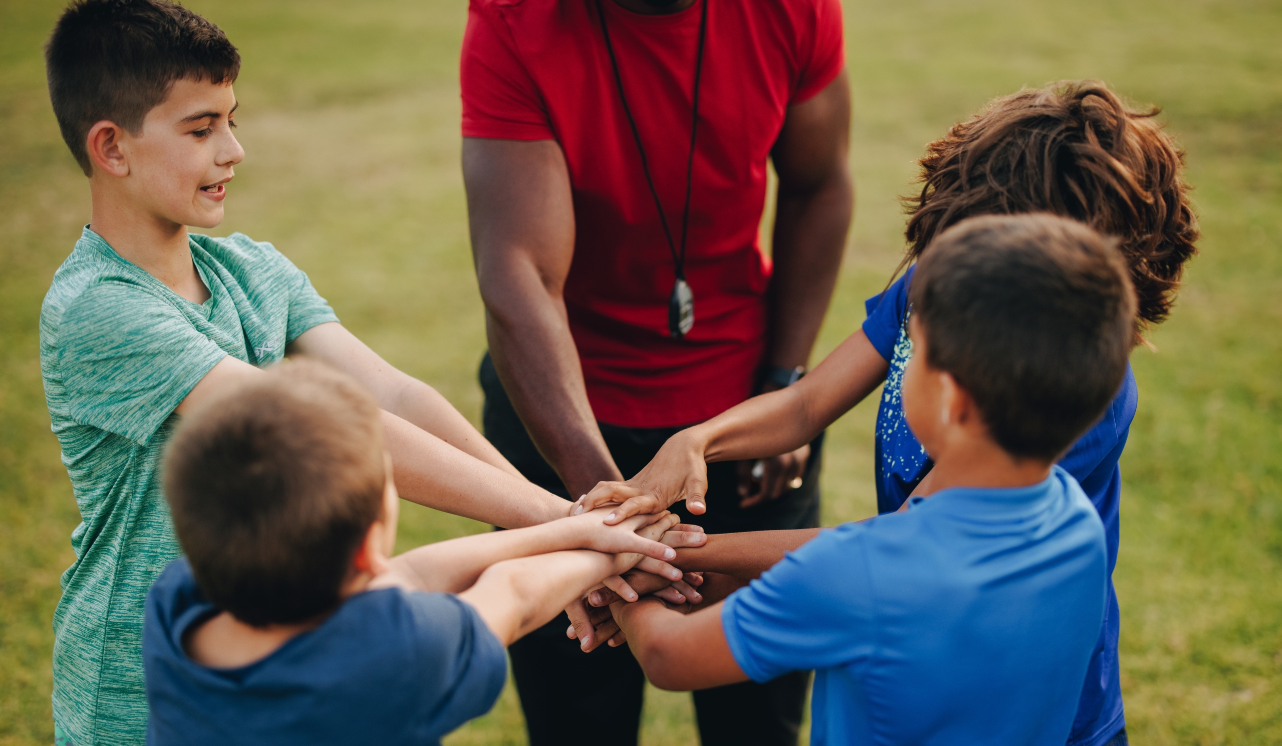 jongens en coach doen een huddle op het sportveld