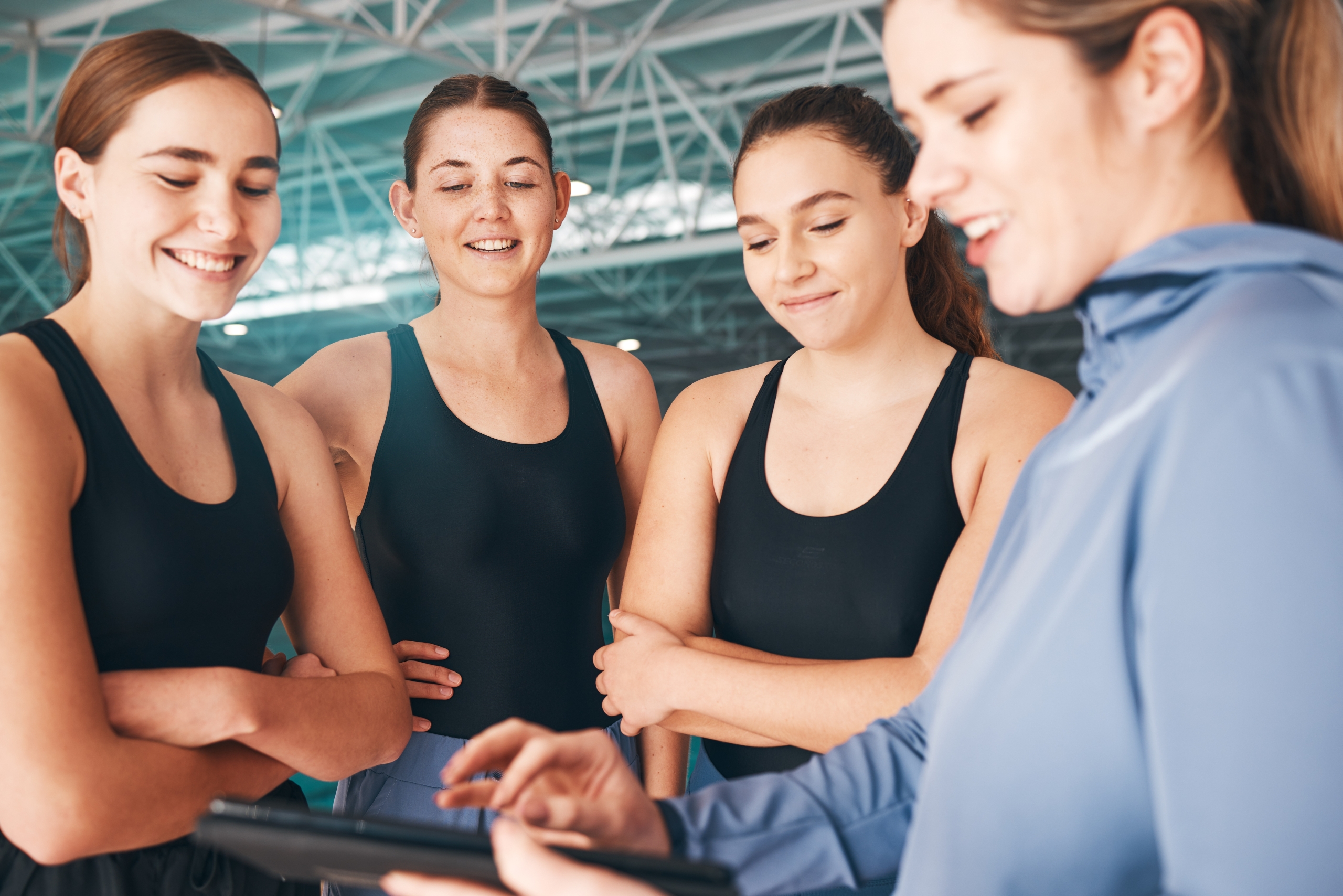 een vrouwelijke coach geeft uitleg aan 3 gymnastes