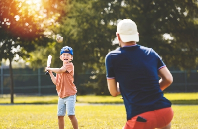 Man en kind spelen baseball op een grasveld