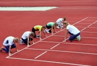 vrouw coacht groep jongeren op atletiekplein