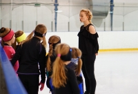 coach spreekt een groepje schaatsers toe