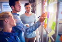 drie teamleden plakken post-its tijdens een brainstorm